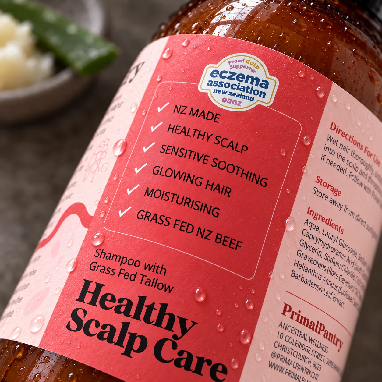 Dewy close-up of the actual shampoo label benefits: NZ made, healthy scalp, sensitive soothing, glowing hair, moisturising, grass fed NZ beef